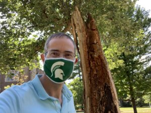 Chris Long in green and white Spartan mask in front of the Resilient Tree