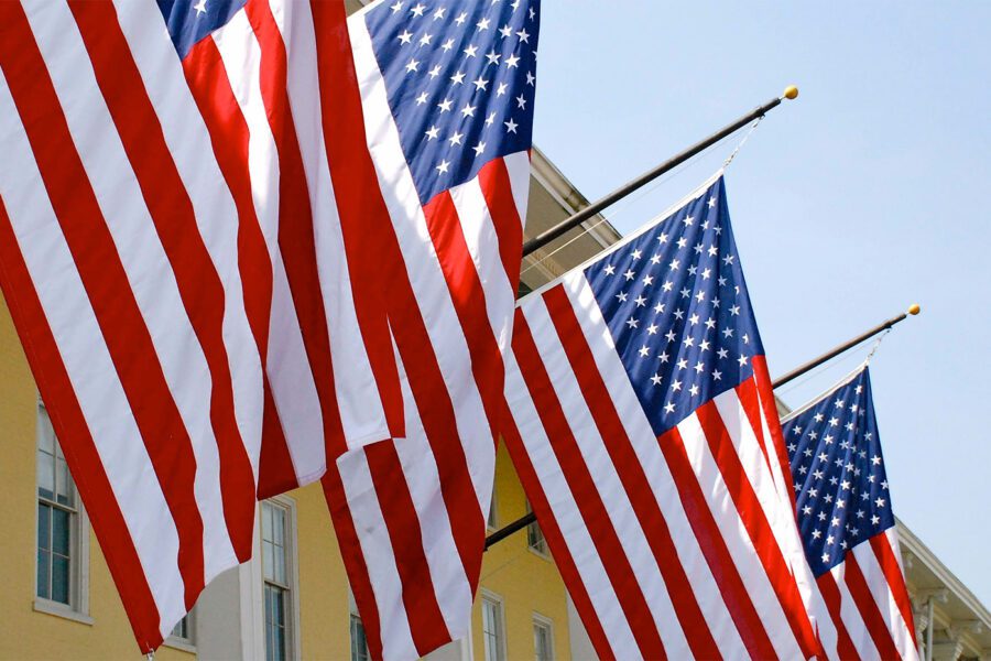 American Flags lined up against a yellow building