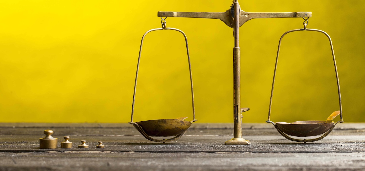 Scales and weights on a wooden table against a yellow background.
